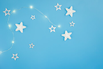 Blue Christmas background with garland and decorative stars, flat lay.