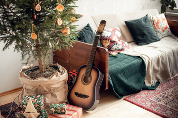cozy vintage New Year's interior with a real live Christmas tree. loft, family celebration at home, dried oranges instead of toys, guitar, retro sofa with decorative pillows