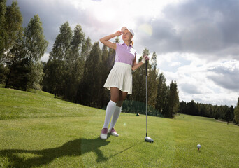 Golfer woman with a golf club before hitting the golf. Club hit. Golf course with rich green lawn and beautiful scenery.