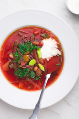 Ukrainian and Russian, Lithuanian, Belarusian and Polish traditional beetroot soup  borscht in bowl in an elegant white plate. Traditional cuisine of the Slavic countries, close-up