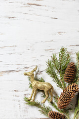 Christmas gold decor, christmas deer and fir tree twigs on a white wood background. View from above. Copy space.