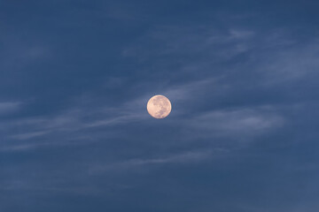 Full moon at blue hour with soft clouds