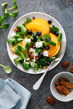 Persimmon fruit salad with blueberry, pecan nuts and ricotta chesse. Healthy food. Top view