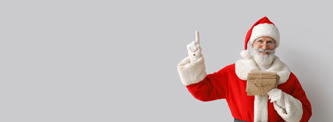 Santa Claus with letters pointing at something on grey background with space for text