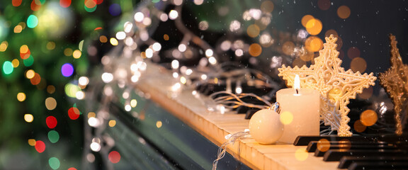 Burning candle and Christmas decorations on piano keys, closeup
