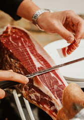 Profesional slicing Spanish jamon iberico (ham). Selective focus point