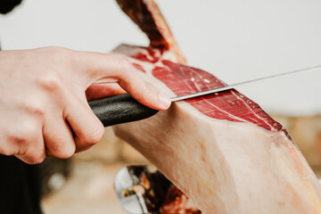 Profesional slicing Spanish jamon iberico (ham). Selective focus point