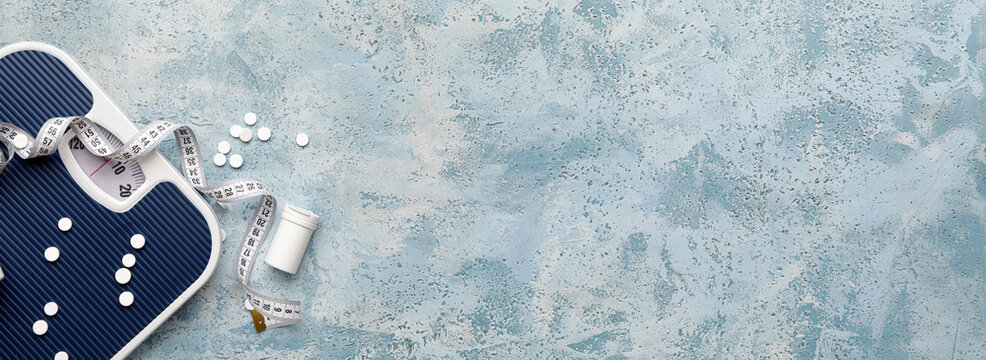 Weight loss pills, scales and measuring tape on light blue background with space for text. Diet concept