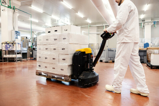 Meat factory worker relocates boxes with meat on the forklift.