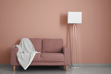 Stylish sofa and floor lamp near color wall in room