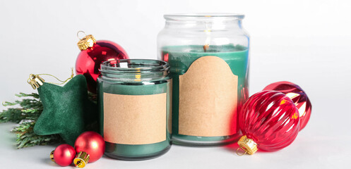 Jars with burning candles and Christmas decor on white background, closeup