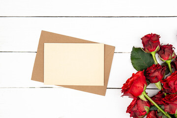 Envelope, blank paper and red roses bouquet, flat lay.