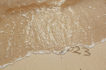 The writing 2023 was erased by the beach waves. New Year's Eve. Merry Chrismast and Happy New Year.