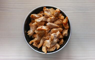 Pieces of fried chicken in a ceramic cup close-up on the background of a light kitchen table