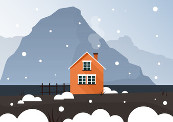 A bright orange small house stands in the snow and behind the blue mountains