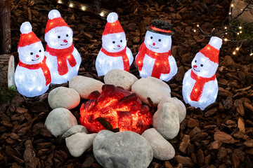 Glowing snowmen in a festive Christmas garden decoration. Bright luminous figurines for children's...