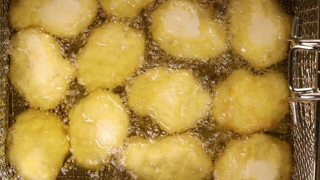 Cooking chicken nuggets are Fried in boiling oil. top view shots