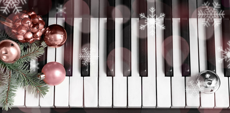 Christmas balls, jingle bells and fir branches on piano keys, top view