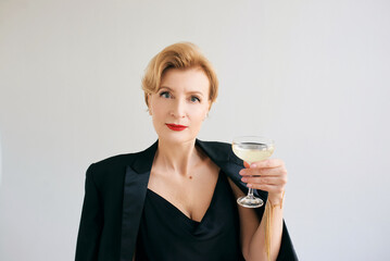 mature stylish elegant woman in tuxedo with glass of sparkling wine. Party, celebration, anti age concept 