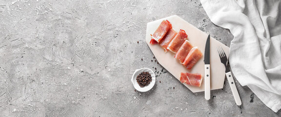Board with tasty ham and spices on light grunge background with space for text