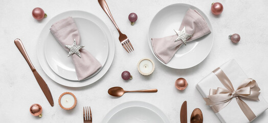 Beautiful table setting with Christmas balls, gift and candles on white background