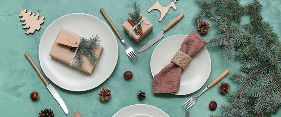Beautiful table setting with Christmas decor, fir branches and gifts on green background - obrazy, fototapety, plakaty