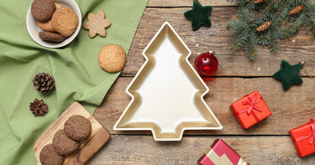 Plate in shape of Christmas tree with cookies, decor and gifts on wooden background