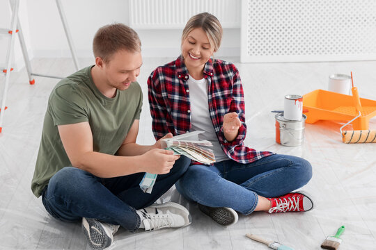 Happy couple with paint chips discussing new wall color in apartment during repair