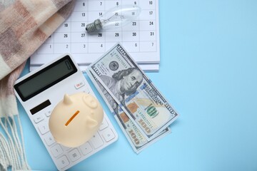 Fototapeta premium Flat lay composition with piggy bank and calculator on light blue background. Space for text