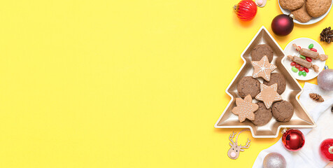 Plate in shape of Christmas tree with cookies, candies and decor on yellow background with space for text