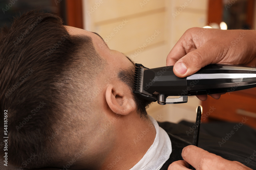 Poster Professional hairdresser working with client in barbershop, closeup