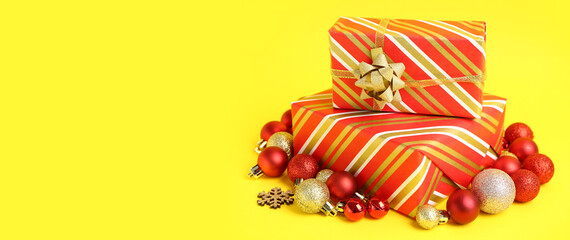 Beautiful Christmas gifts and balls on yellow background with space for text