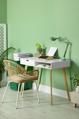 Writer's workplace with typewriter on wooden desk near pale green wall in room