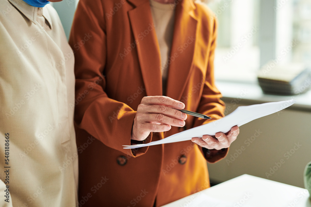 Poster hand of mature teacher of foreign language pointing at document with grammar test while explaining i