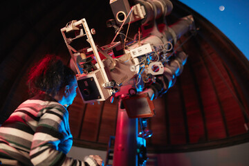 Astronomer with a big astronomical telescope in observatory doing science research of space and...
