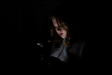 Fototapeta na wymiar Blackout. Girl using smartphone in dark room