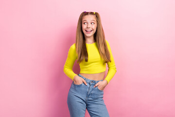 Portrait of impressed girl straight hair dressed yellow long sleeve look empty space hands in pockets isolated on yellow color background