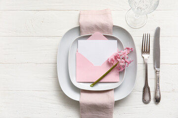 Table setting with blank card and hyacinth flower on white wooden background