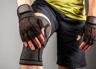 Athlete wearing knee support brace, elastic kneecap bandage, orthopedic sleeve for compression,...