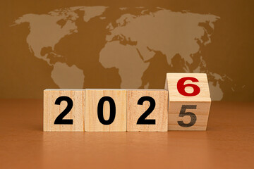 Wooden cubes with the letters 2025 change to 2026 on brown background