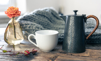 Cozy composition with a teapot and a cup of tea in the interior of a kitchen.