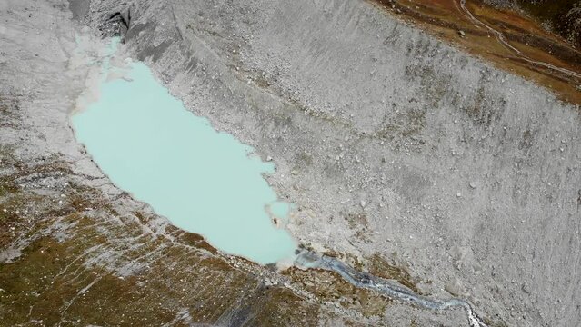 Aerial view of the Moiry glacier near Grimentz in Valais, Switzerland with a pan up from the small glacial lake up to the ice and mountain peaks hiding in clouds