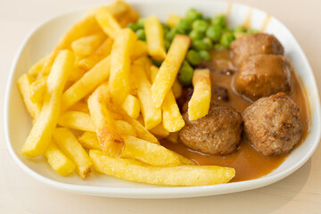 Meatballs with French Fries, Green Peas, Bechamel Sauce on White Plate