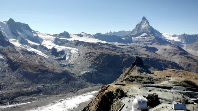 Aerial flyover over Gornergrat in Zermatt, Switzerland with view of the train station and of the famous observatory along with the famous Matterhorn in the background.