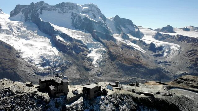 Aerial spinning view around Gornergrat in Zermatt, Switzerland with a view of the Matterhorn, Monte Rosa, Gorner glacier, observatory and train station on a sunny day in the Swiss Alps.