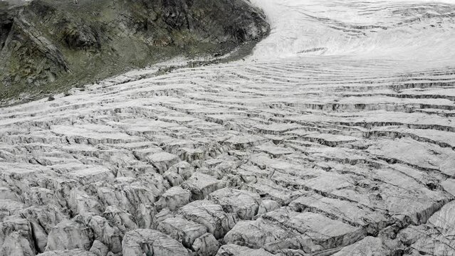 Aerial flyover above the Moiry glacier near Grimentz in Valais, Switzerland with a pan down view towards icy crevasses cloudy summer day