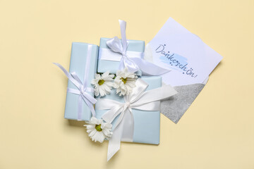Card with text DANKE SCHON, gift boxes and flowers on beige background