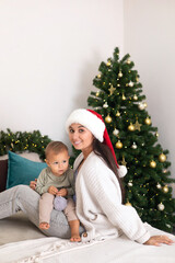 Merry Christmas. Beautiful Mother and little daughter in a bedroom decorated for the holiday. Happy family. Lifestyle