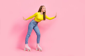 Full length photo of charming excited school girl dressed yellow crop top riding rollers empty space isolated pink color background