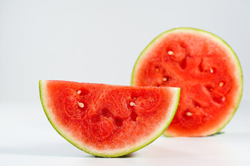 Red watermelon slice close-up on white background, space for text. Half of a ripe scarlet watermelon fruit with red juicy flesh and seeds turned sideways in profile, text space above.